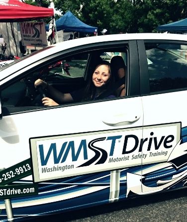A WMST Drive student smiling behind the wheel of the training car